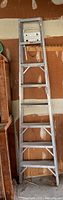 Full view of the eight foot Reynolds aluminum step ladder standing upright in garage environment against wood panel wall, showing height and structure