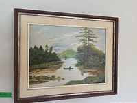 Full view of the framed landscape painting hung on a wall showing the overall composition and frame details.