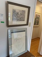 Both framed pieces hanging on wall, showing landscape print above and portrait sketch below.