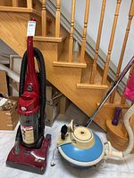 Photo of both vacuums under stairs showing the full units including upright and canister styles