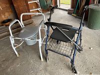 Blue collapsible walker with black seat, metal wire carry basket, and white commode chair with gray lid and basin visible in garage setting.