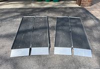 Two ramps fully opened flat on driveway showing black non-slip surface and silver end plates.