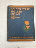 Front cover of the 1935 Golden State Speller Book One teachers manual with blue cloth cover and orange floral design.