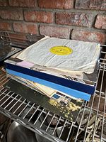 Image showing a stack of vinyl records including a white label record on top and several colorful cardboard and paper sleeves