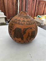 Side view of hand carved African gourd vase showing bird and geometric patterns