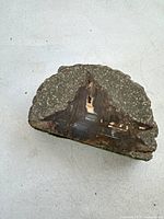 Front view of one piece of agate hardstone with rough outer texture and polished interior showing a hollow cavity.