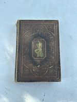 Front cover of antique reference workbook with embossed design and an inset image of 'The Thinker' sculpture.