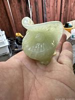 Close-up of the front and side of carved jade owl showing detailed facial features and smooth polish.