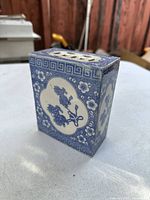 Blue and white porcelain rectangular piece with floral motifs and geometric border, shown on white surface.