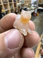 Front view of the carved stone cat netsuke showing detailed facial carvings and translucent material.