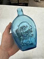 Front side of blue glass flask bottle showing embossed portrait of George Washington