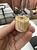 Ox bone piece held in hand showing carved linear patterns along side, top with a circular hole and geometric design.