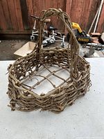 Full view of primitive antique hand woven basket with twisted vine handle and lattice base.