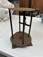 Side view showing rusted forged iron construction with base and vertical supports.