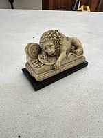 Side view showing entire lion statue on black glass base with small corner chip