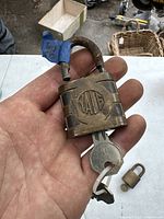 Close-up photo of an antique Yale brass padlock in palm with a key attached, showing engraved Yale logo and patina.