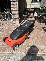 Full view of the Black and Decker Lawn Hog electric lawn mower showing orange and black body, wheels and handle.