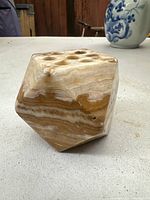 Multi-sided carved onyx candle holder resting on a white surface with visible natural brown and beige banding.