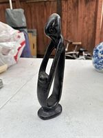 Full view of the elongated black stone mother and child statue with open frame design