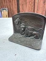 Photo of the antique cast metal lion bookend showing the lions and background in relief detail on one face.