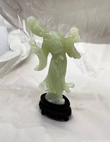 Full view of the jade serpentine Guanyin figurine standing on its wooden base, showing transparency and color tone of the material.