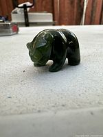 Side view of carved nephrite jade bear showing detailed features and polished surface.