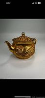 Front side view of the gold gilt bronze teapot showing dragon and phoenix decorative relief