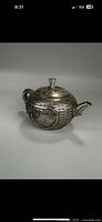 Teapot with lid on, showing woven grass texture and spout