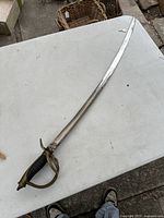 Full view of US Civil War style cavalry sword showing curved blade, brass guard, and leather handle.