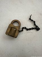Brass Corbin padlock with chain on white surface