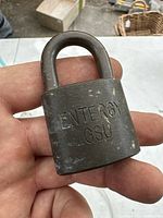 Close-up of the padlock held in hand showing 'Entergy GSU' engraving and surface wear.