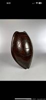 Front view of hand carved dark brown wooden sea turtle shell sculpture with detailed shell segments. Heavy and dense wood with smooth polished finish.