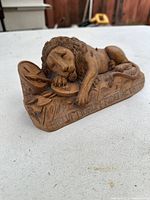 Photo of the carved wooden lion lying on its side showing full figure, inscription, and detail.