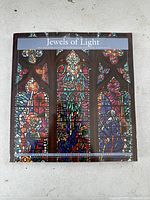 Front cover of the hardcover book titled 'Jewels of Light' showing stained glass artwork.