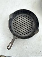 Top-down view of the round cast iron griddle pan showing the ridged cooking surface, pouring spouts, and handle.