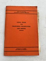 Front cover of orange booklet titled 'Legal Guide for California Prospectors and Miners (Reprint)', showing publisher info and condition.