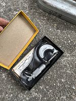 Machinist micrometer with its original yellow box and clear molded plastic holder, showing the full tool with adjustment knob and scale markings.