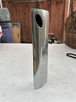 Front view of a narrow, solid cast aluminum modern vase or statue with angled oval top opening.