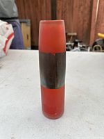 Front view of the modern cylindrical glass vase showing frosted red glass and silver metal band.