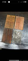 Four brass print plates on floor, showing front side with raised printing areas and patina.