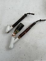 Pair of antique pipes with porcelain bowls and wooden stems, both with painted decoration.