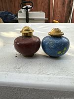 Pair of red and blue antique Chinese salt and pepper shakers with brass tops, shown outdoors on a flat surface