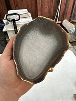 Polished agate sample showing full oval shape and color contrast between outer band and crystalline core held in hand