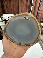 Polished genuine agate quartz slab held in hand showing natural banded pattern and polished surface.