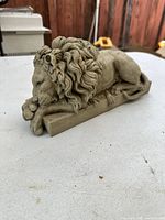 Front and side angled view of the sleeping lion statue showing detailed mane, resting pose, and textured surface.