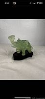 Elephant jade statue on dark wooden base angled view