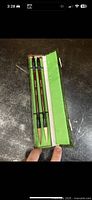 Two Chinese calligraphy/watercolor brushes in green fabric-lined box, showing fine tips and wooden handles with bone colored components.