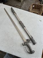 Full view of the vintage dragon fantasy sword alongside its sheath on a flat surface.