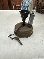 Vintage brass gas camping stove burner on a table showing overall design and fuel tank.