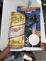 Vintage Miller King Kan beer poster lying flat showing a large can and gorilla with some creases and wear.